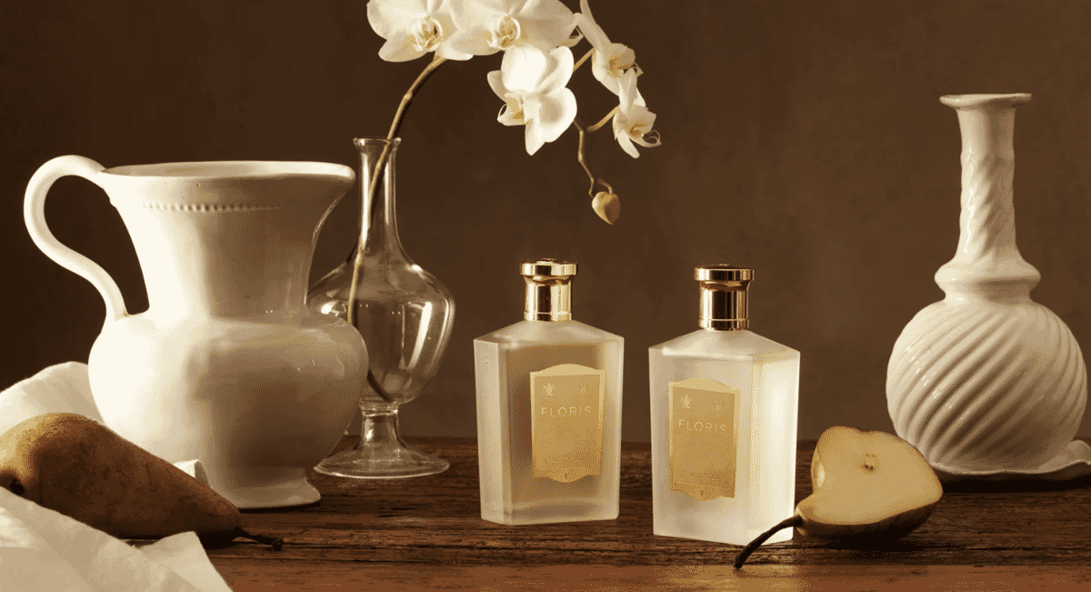 Still life of Floris perfume bottles with floral and fruit accents.