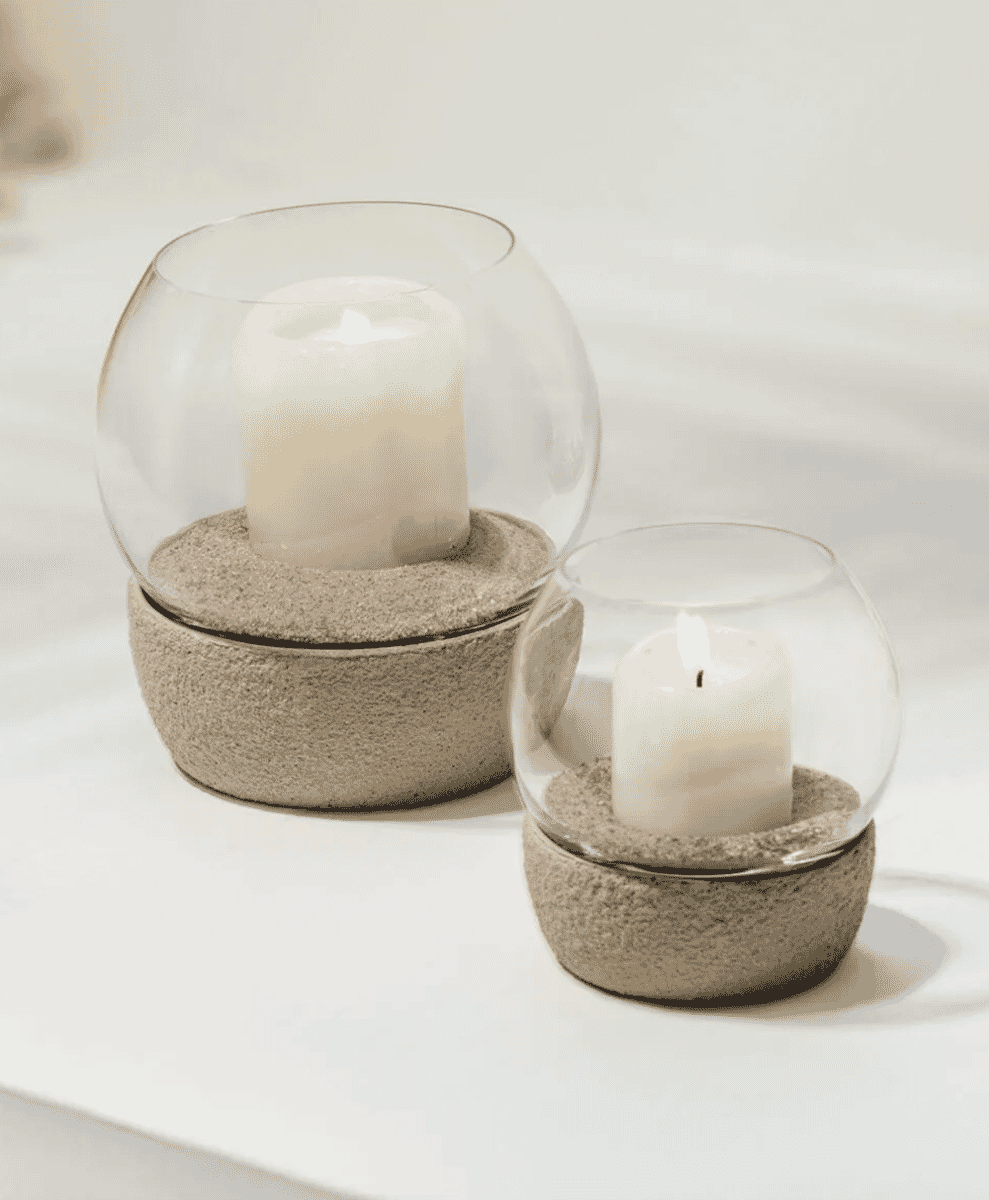 Two glass dome candle holders with textured stone bases on a white surface.