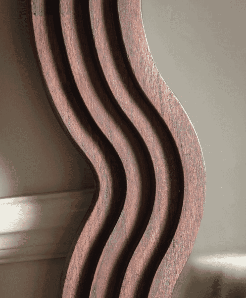 Close-up of dark wood decorative piece with rich grain and wavy grooves.