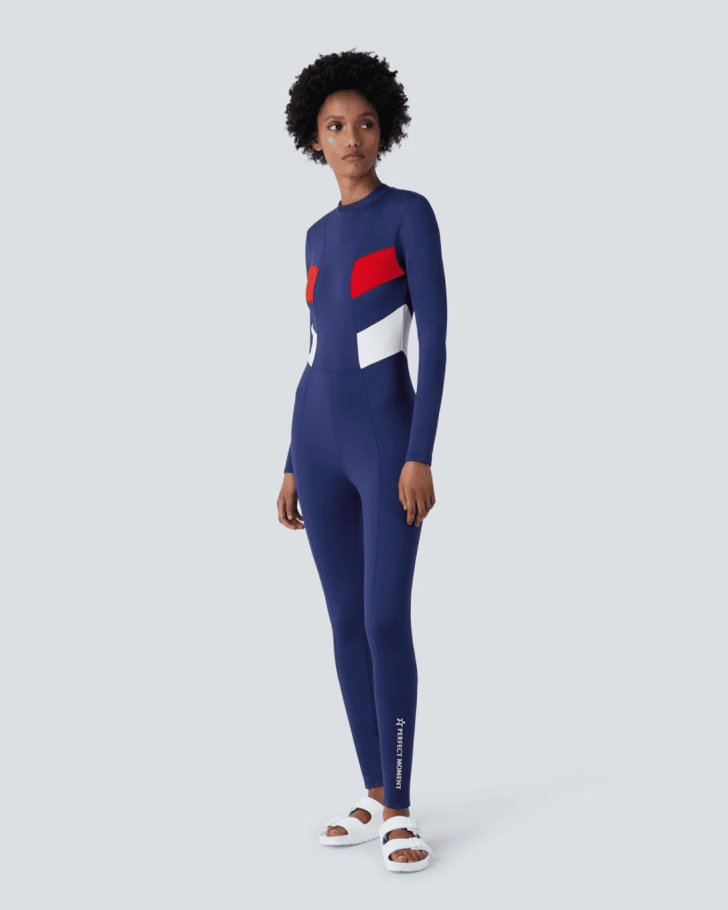 Model wearing a navy blue and red geometric patterned full-body wetsuit.