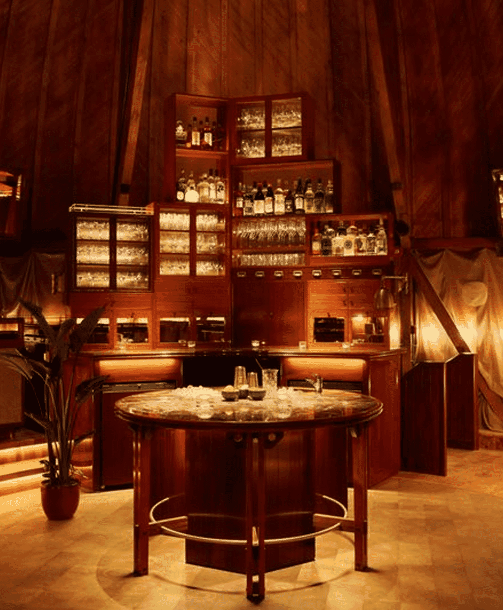 Wood-paneled bar interior with vintage cabinets stocked with premium liquor.