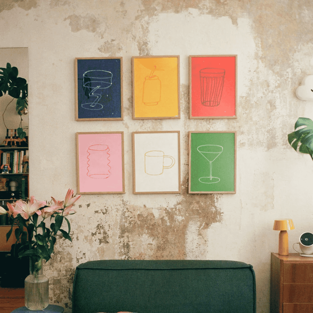 A cozy living room featuring colorful drinkware prints and green indoor plants against a textured wall.