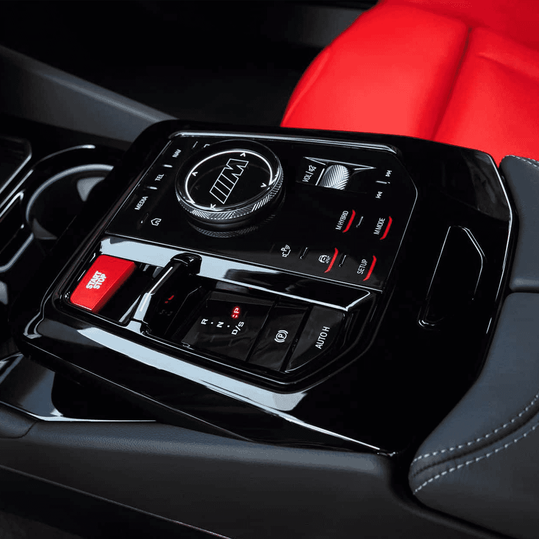 Close-up of the center console in the BMW M5 Touring with red and black leather and a carbon-trimmed gear selector.