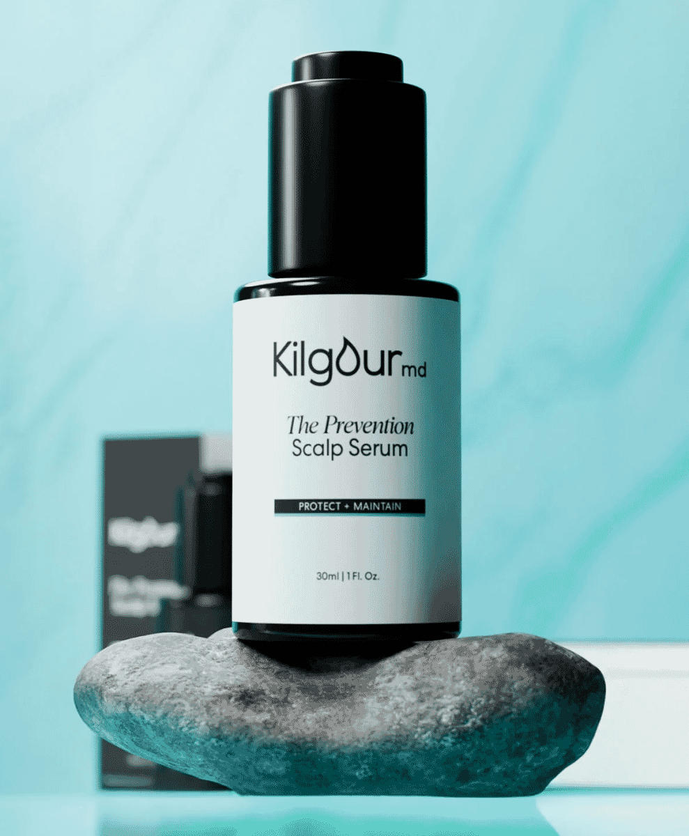 Sleek black bottle of Kilgour MD scalp serum on a stone against a turquoise background.