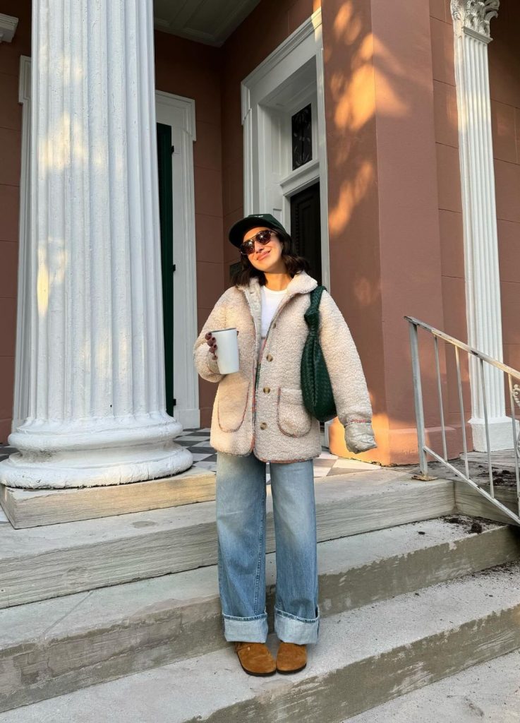 @aprillockhart wearing cuffed blue jeans and Birkenstock clogs in an outdoor setting.