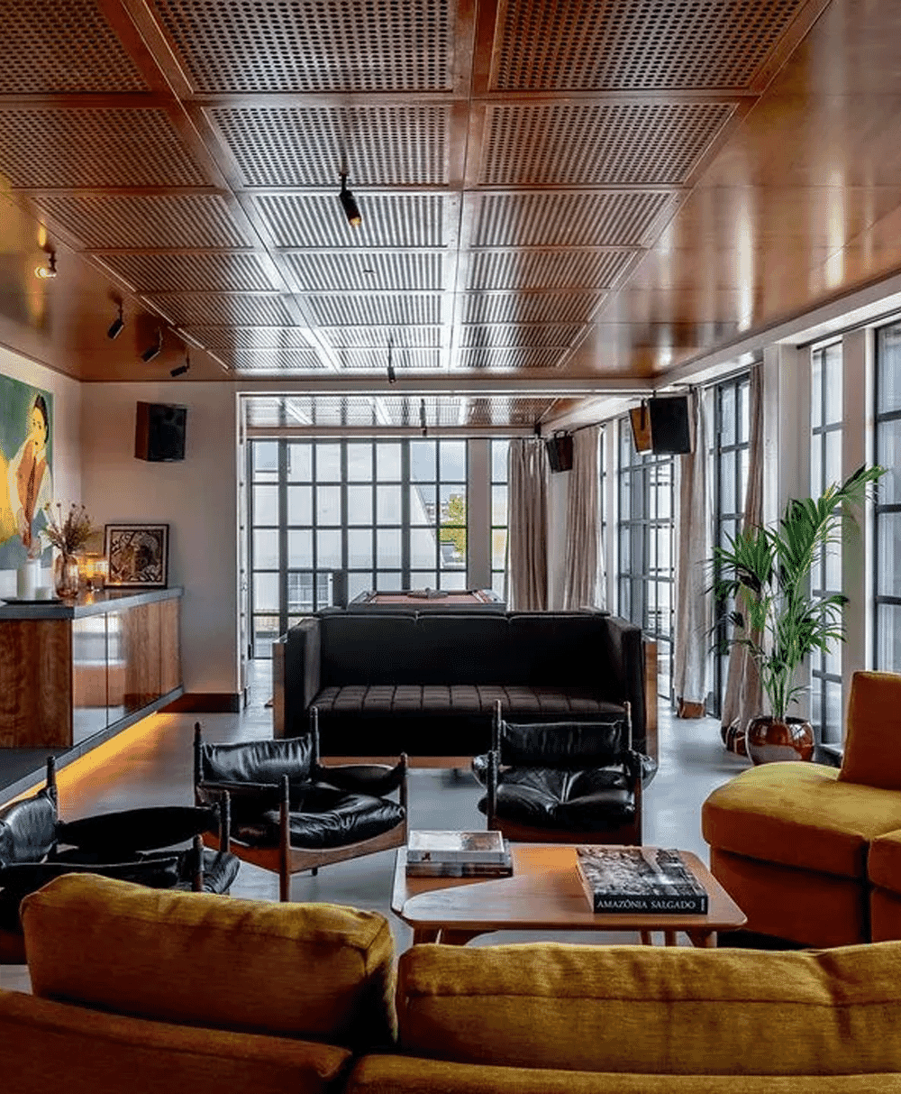 A modern living room featuring mustard yellow sofas and black leather chairs.