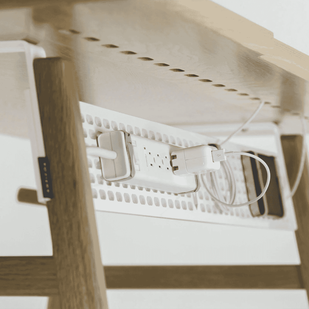 Under-desk cable management system with organized white power strips and cables.
