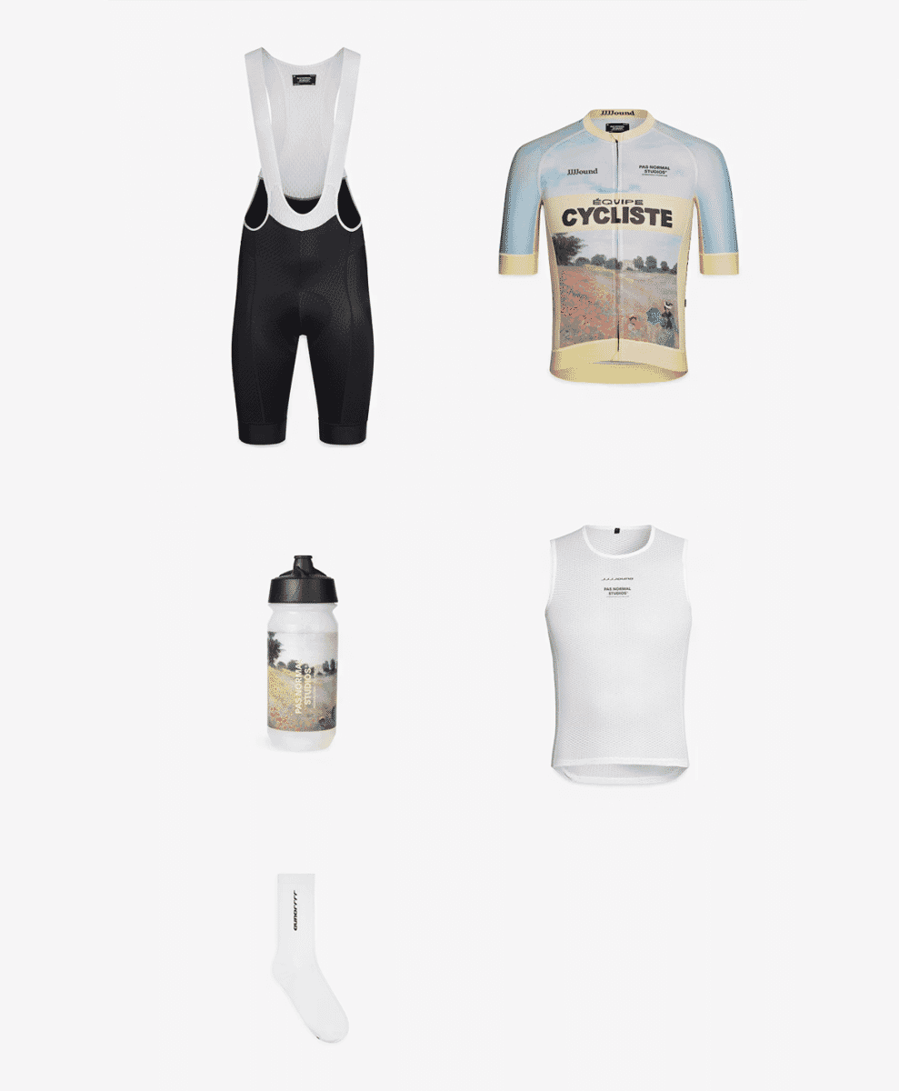 A flat lay image of black bib shorts, a graphic jersey, a white base layer, a branded water bottle, and white socks.