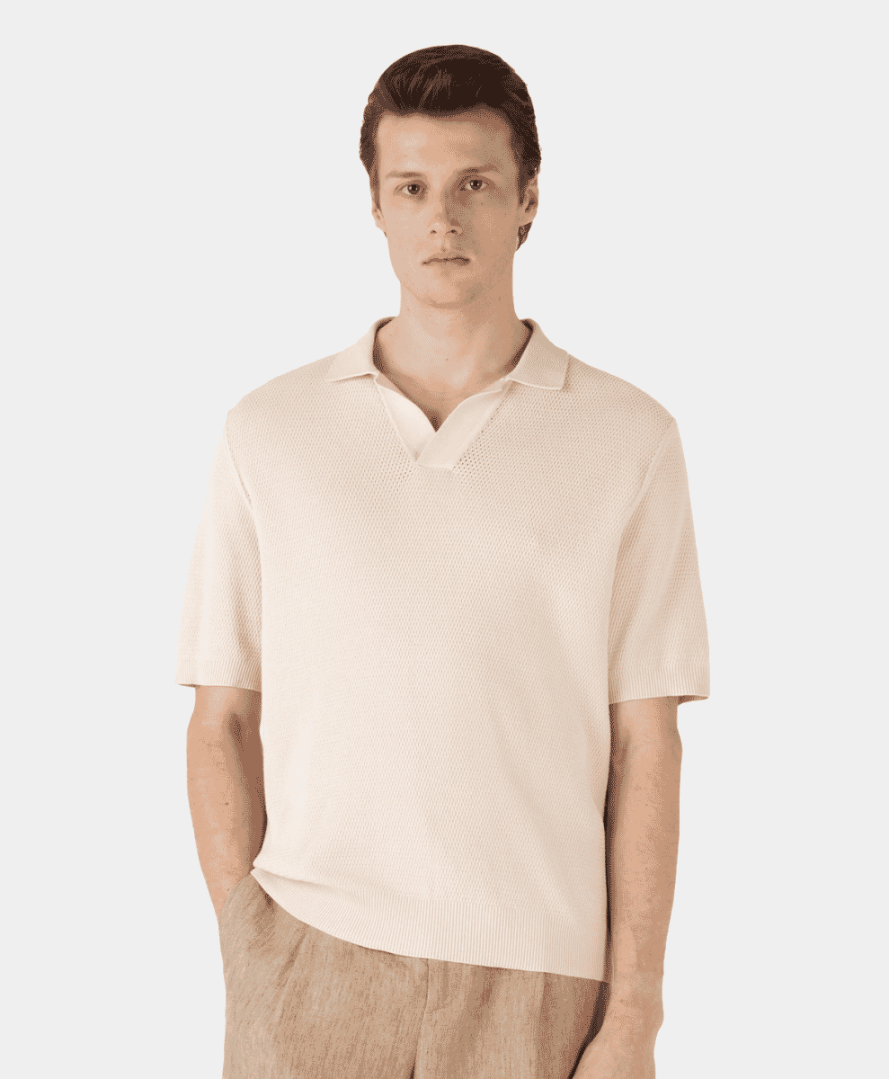 A man models a cream-colored knitted polo shirt with a textured weave.