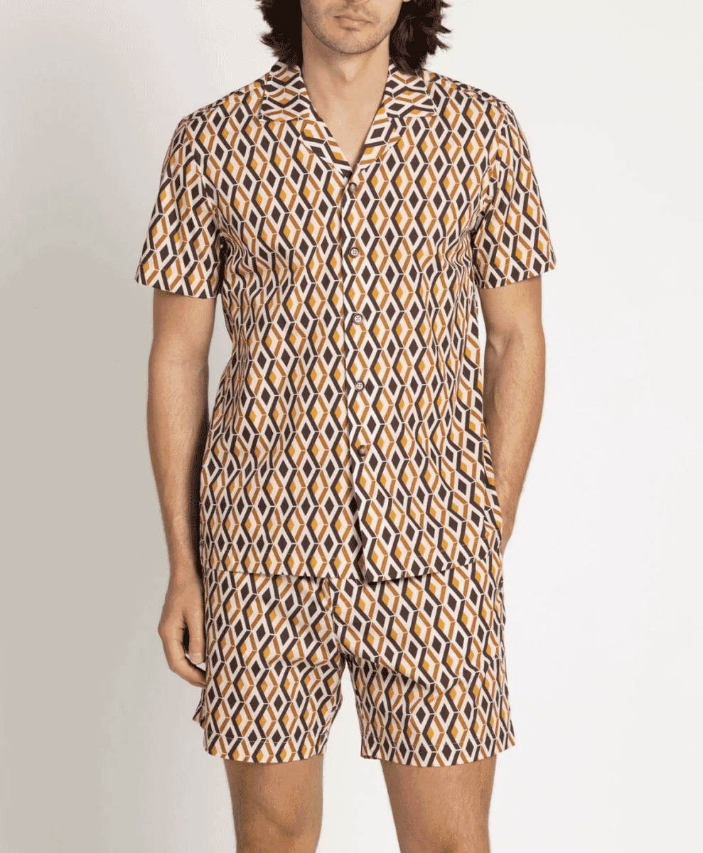 A man wearing a matching geometric print shirt and shorts set in brown and orange tones.