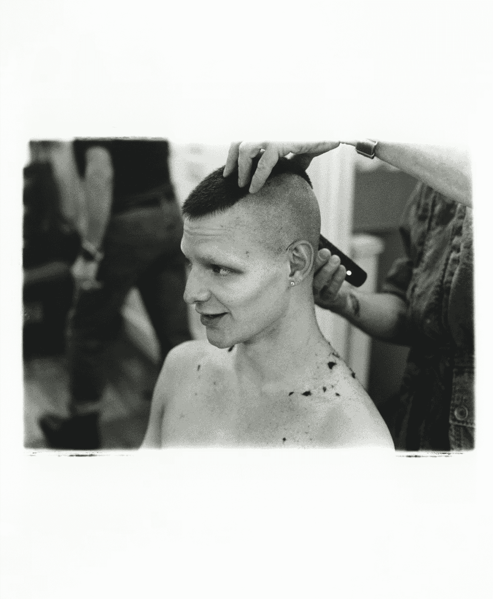 A person receiving a close-cropped haircut in a salon setting, emphasizing a grooming transformation.