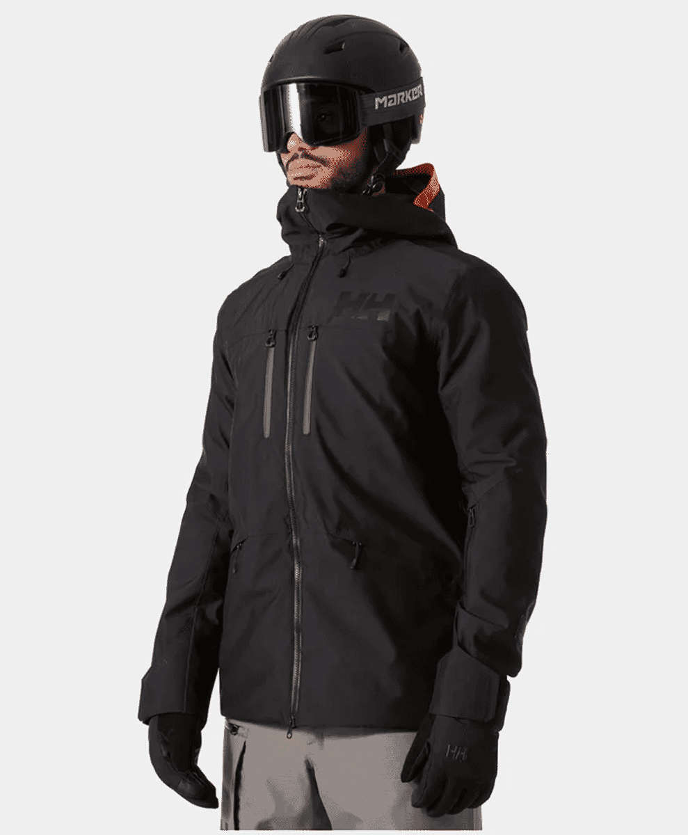 Male model in a full black Helly Hansen ski outfit with helmet and goggles.