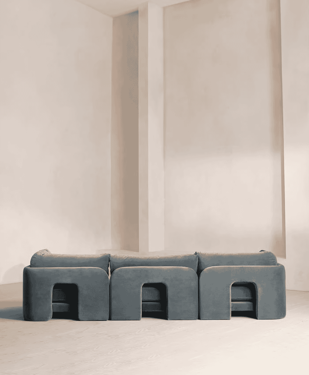 Modern gray modular sofa with geometric cutouts in a white minimalist room.