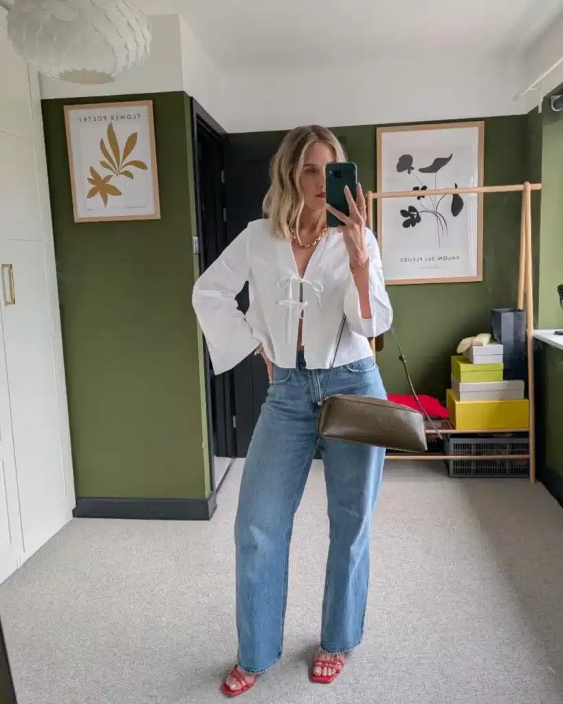 Mirror selfie of a woman in a white bell-sleeve blouse and red sandals.