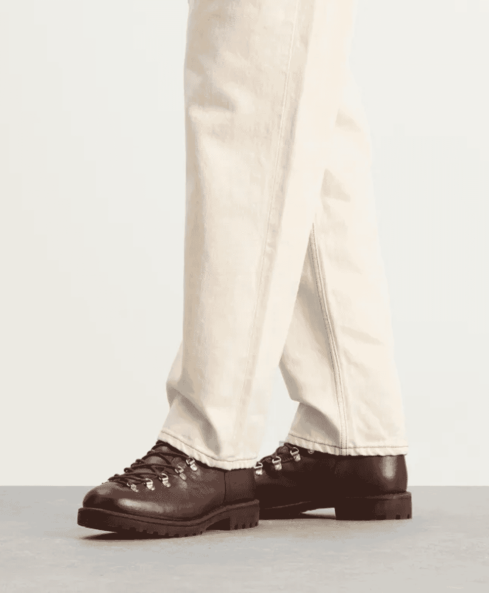 Close-up of a person wearing dark brown leather hiking boots with metal eyelets.