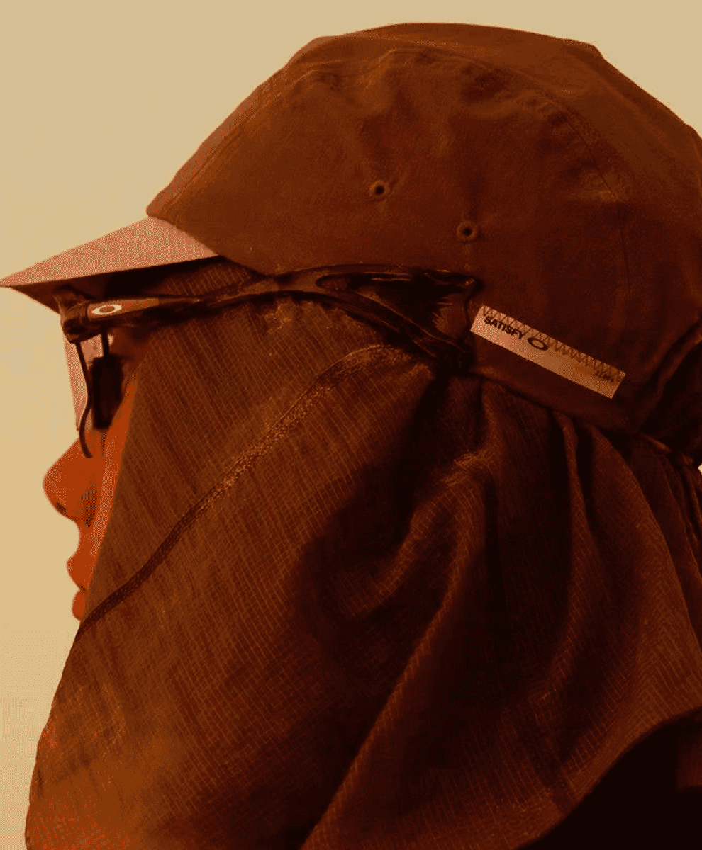 Profile view of a person wearing a brown sun hat with a neck flap and athletic sunglasses.