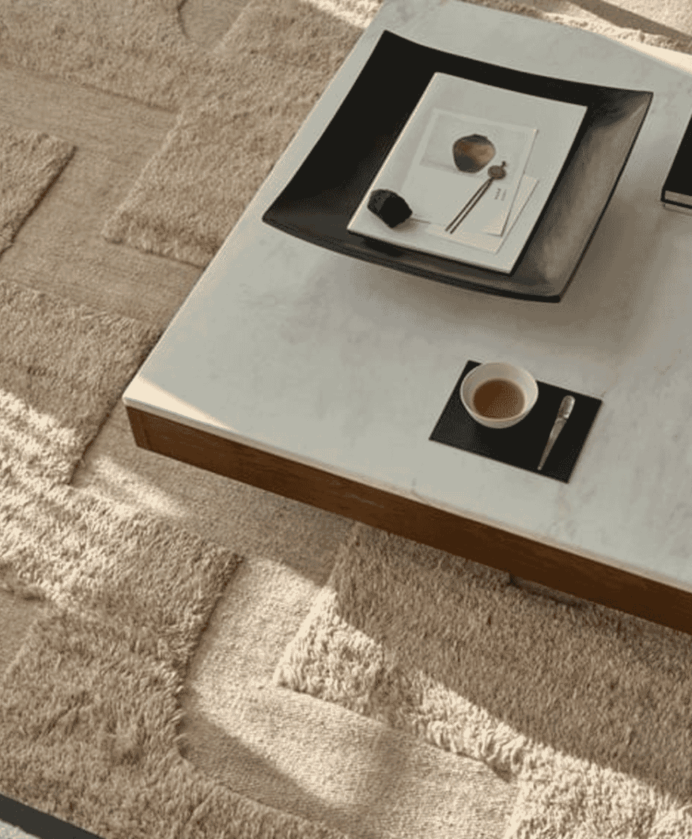 Minimalist coffee table featuring a black tray with a book, decorative stone, and a teacup.