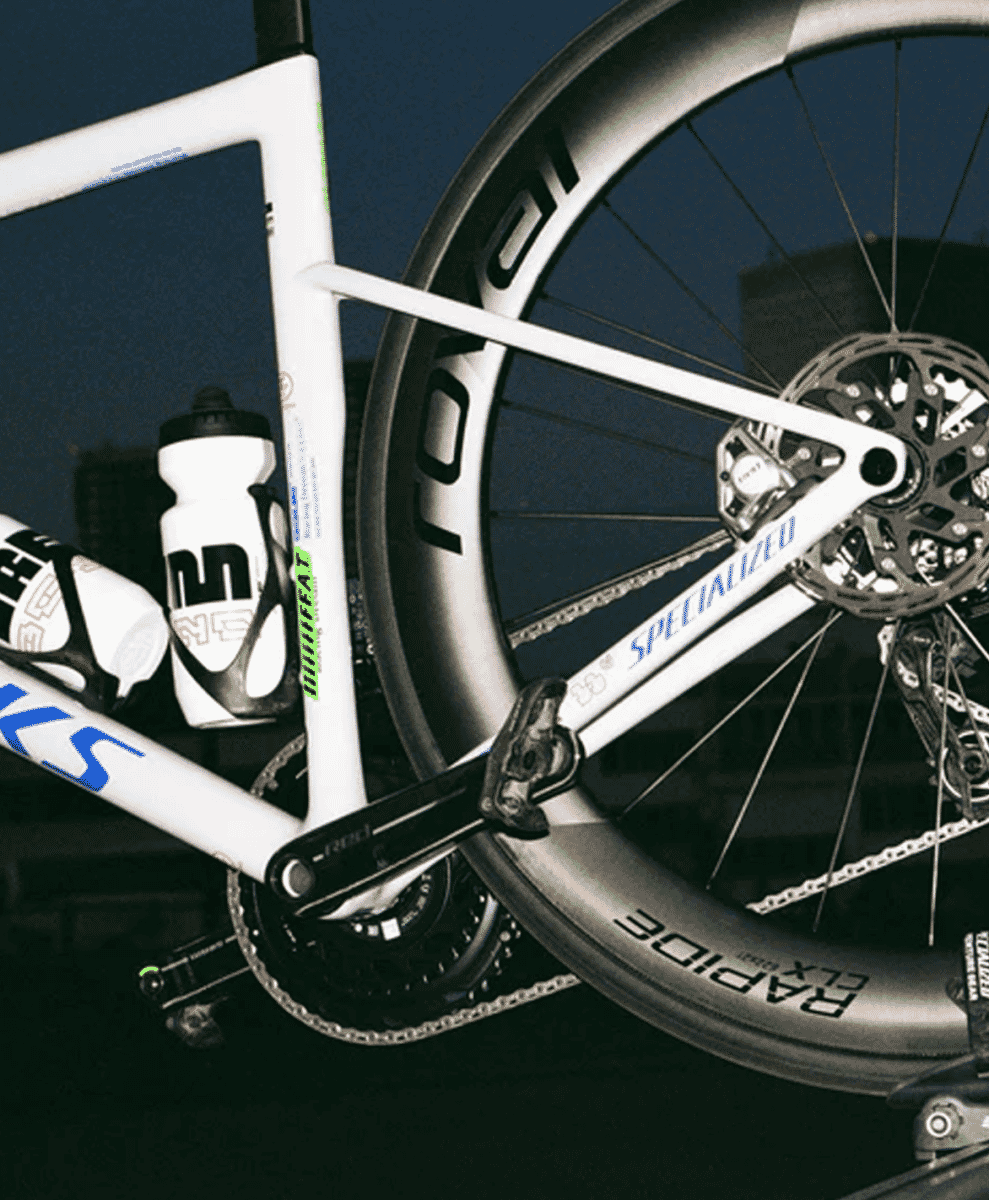 Close-up of a white Specialized road bicycle with Rapid CLX wheels and sleek frame design against a dark background.