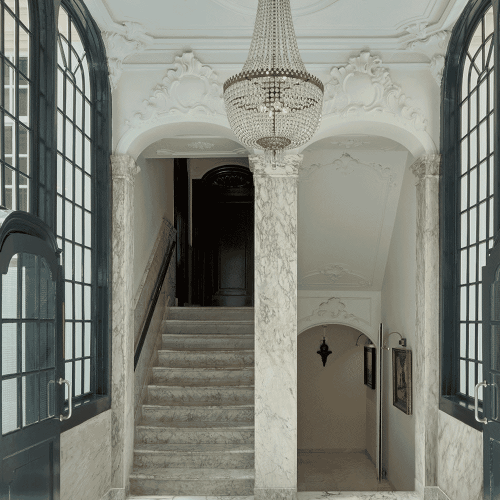 Ornate classical interior featuring a grand marble staircase and crystal chandelier.
