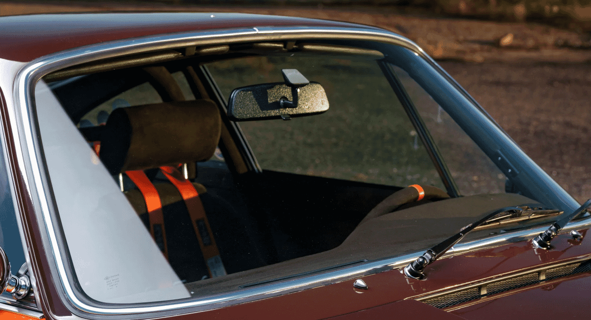 Close-up of brown suede racing seats with orange RJS competition harnesses.