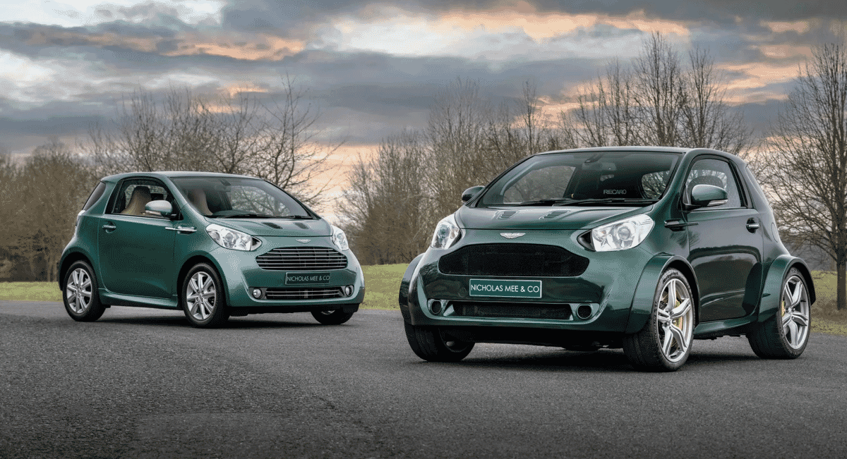 Two customized green Aston Martin Cygnet cars parked together under a cloudy sky.