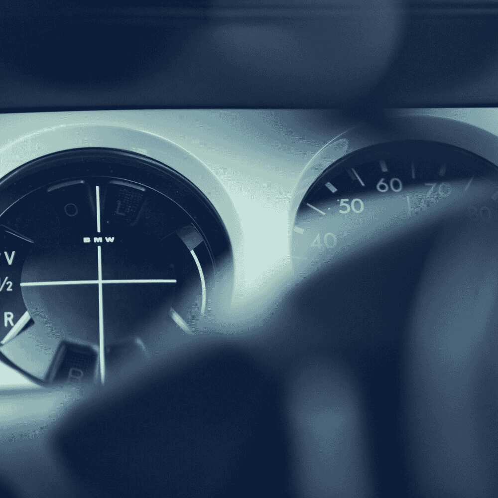 Automotive dashboard featuring a speedometer and fuel gauge under cool blue lighting.