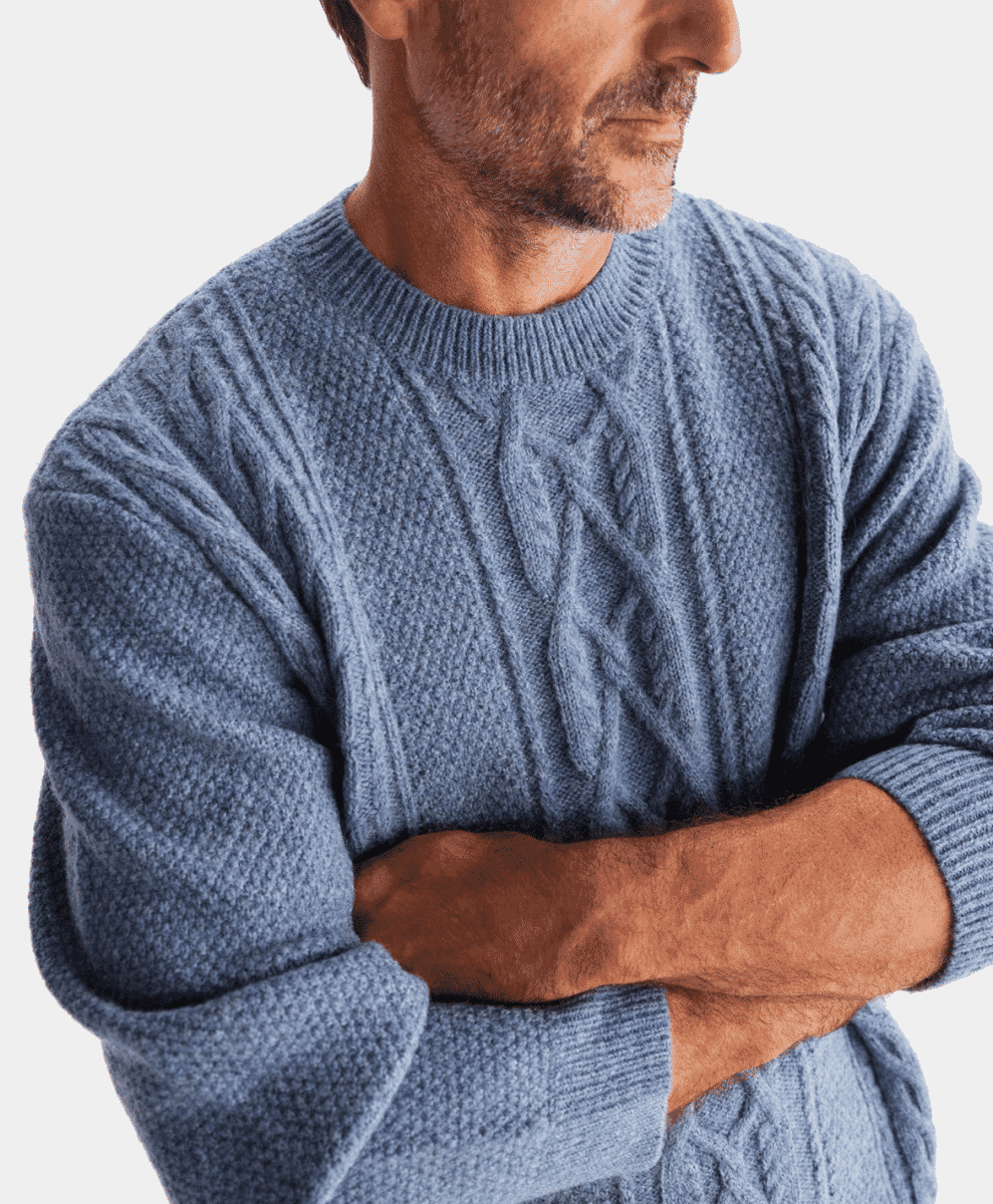 Close-up of a man wearing a light blue cable-knit sweater with prominent ribbed texture.