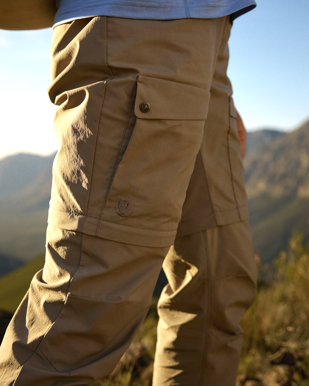 Close-up detail of Fjällräven beige cargo pants showcasing the functional flap pocket and fox logo.