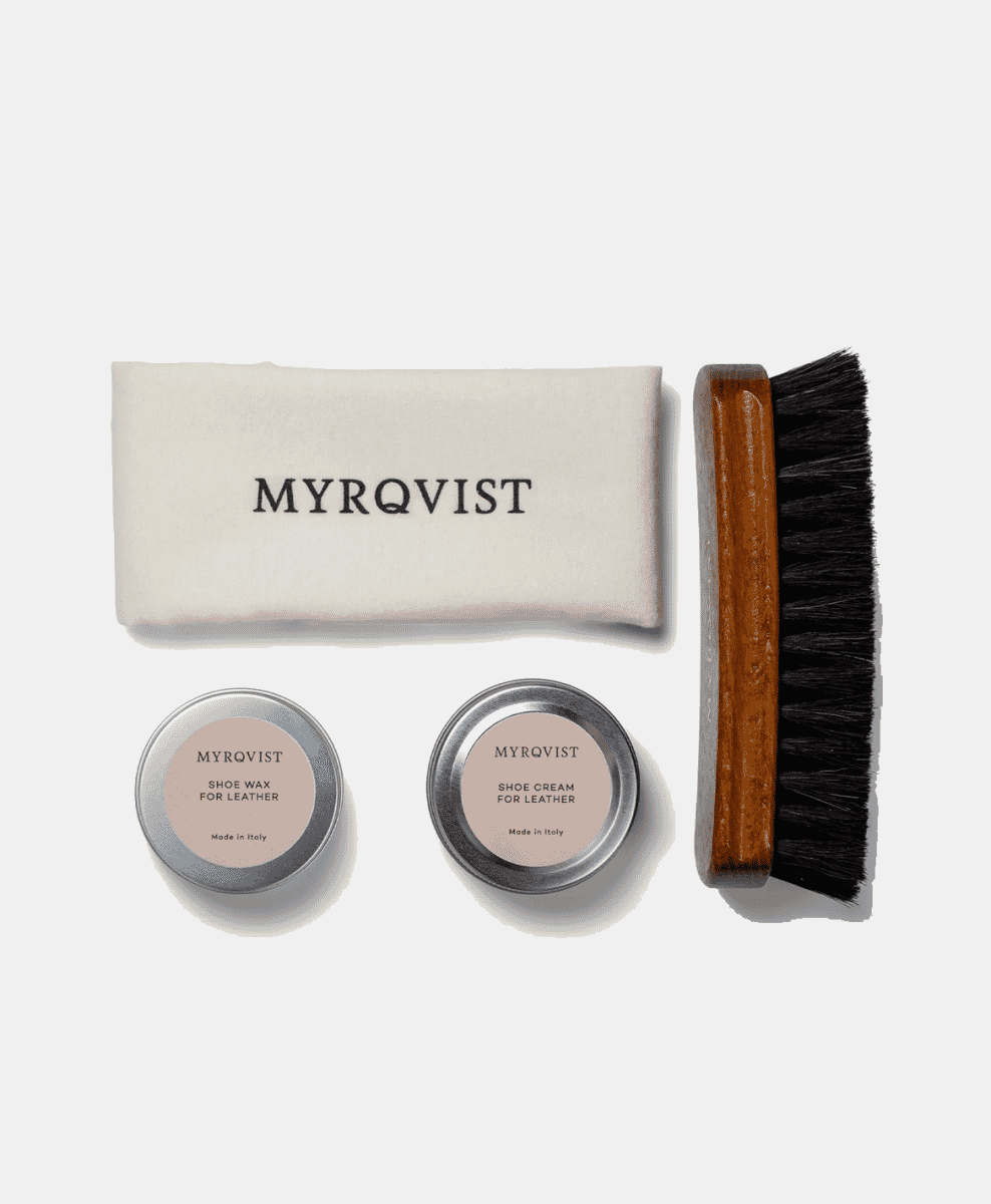 Flat-lay shot of a leather shoe care kit including wax, cream, and brushes.