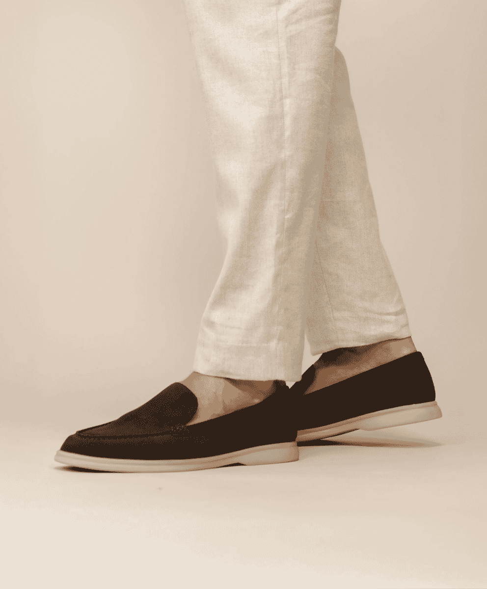 Close-up of dark brown suede loafers paired with linen trousers.