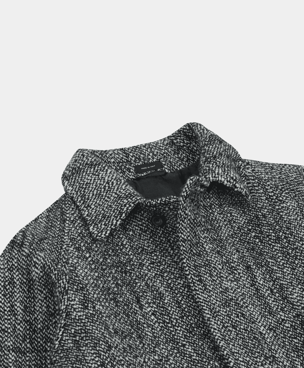 Macro shot of a herringbone wool coat collar with a 'Made in Italy' label.