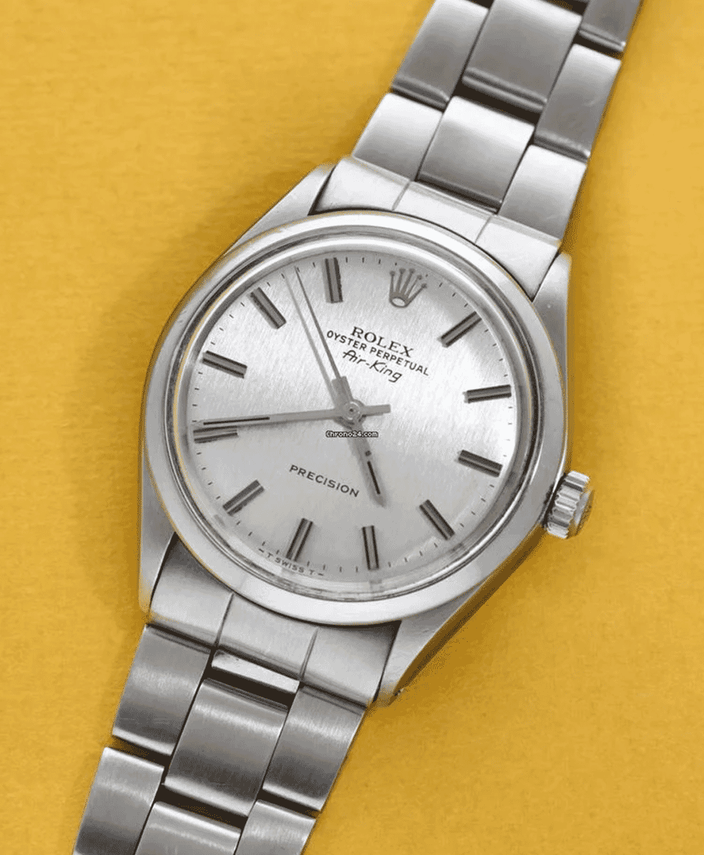 A stainless steel Rolex Air-King 5500 displayed against a warm yellow background.