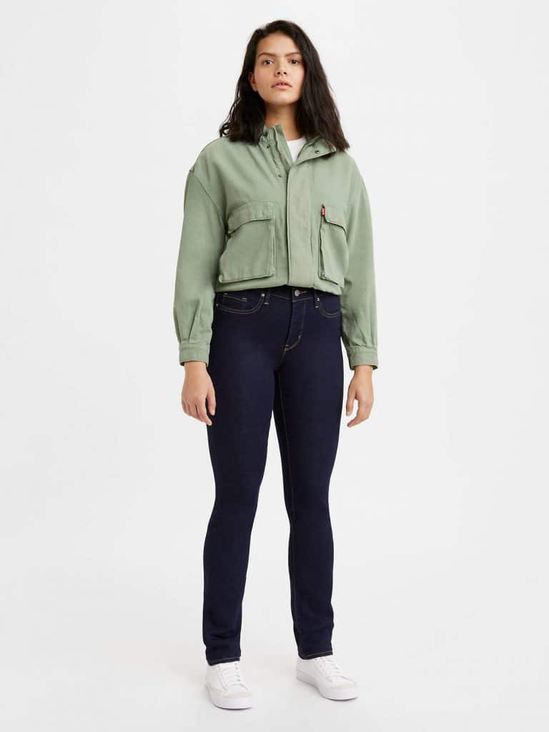 Woman in a cropped olive green utility jacket and dark denim.