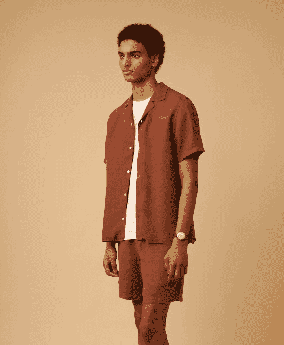 A man in a studio wearing a brown camp-collar shirt and matching linen shorts.