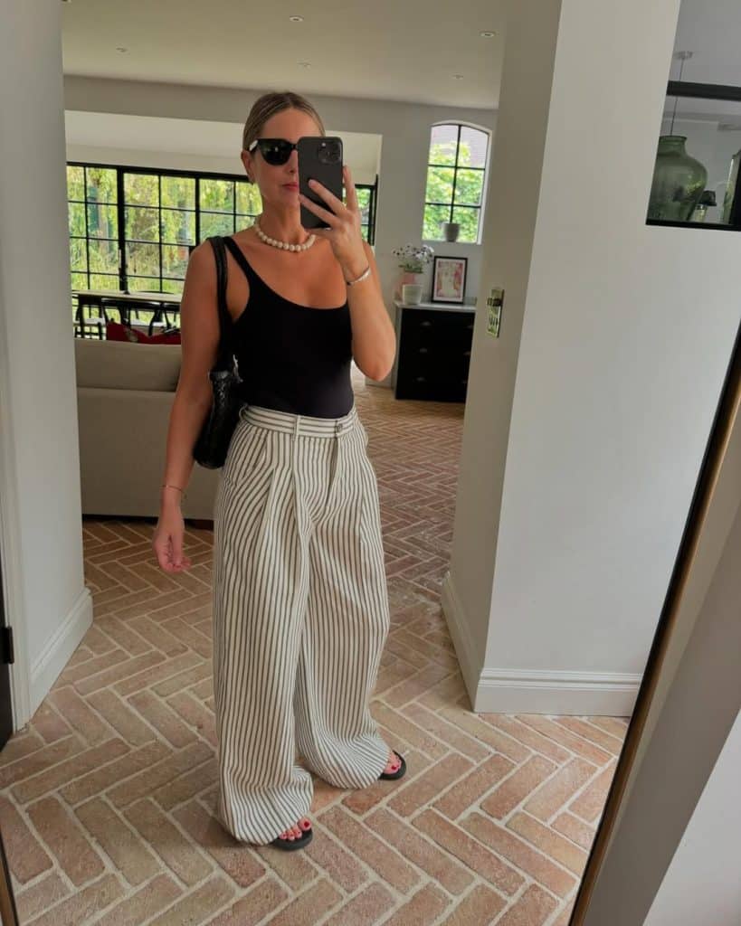 Chic city street style featuring tailored high-waisted shorts and flat leather sandals.