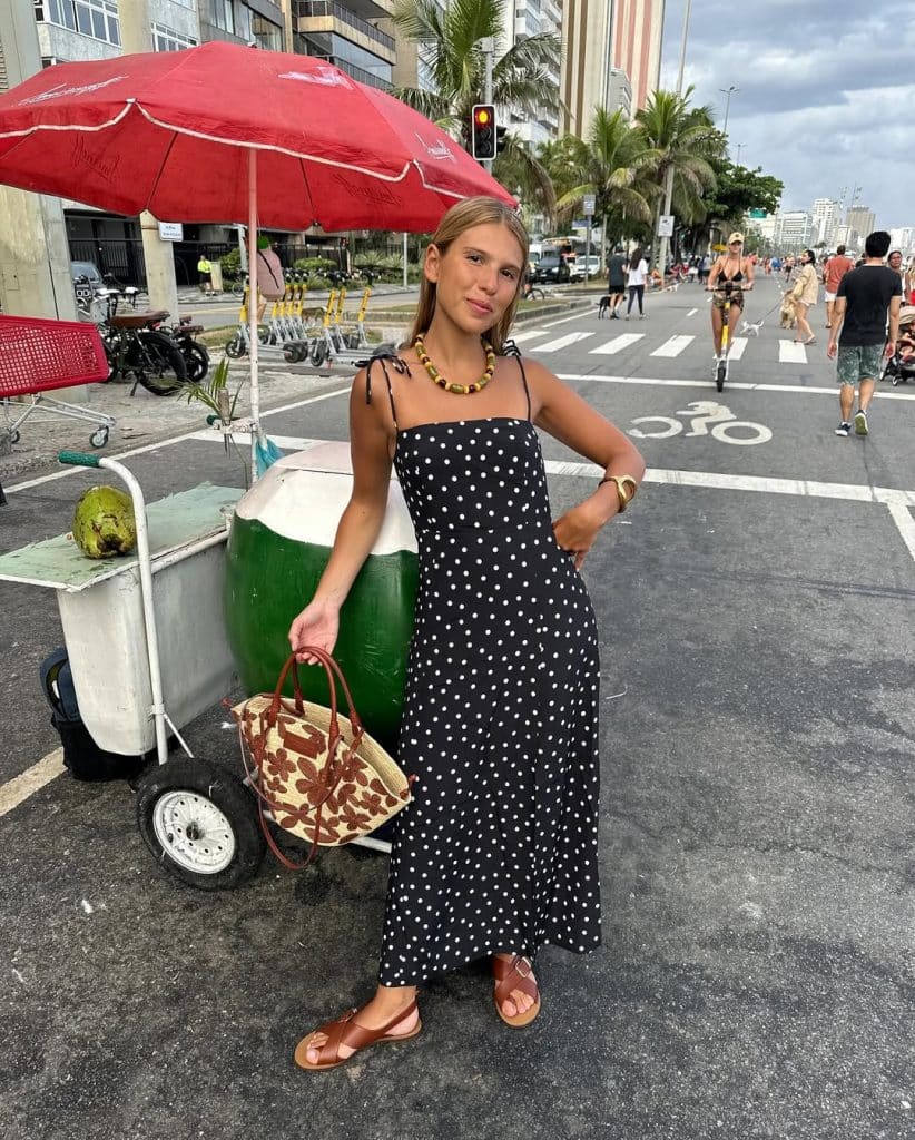 Woman in a black polka-dot maxi dress on a city street.