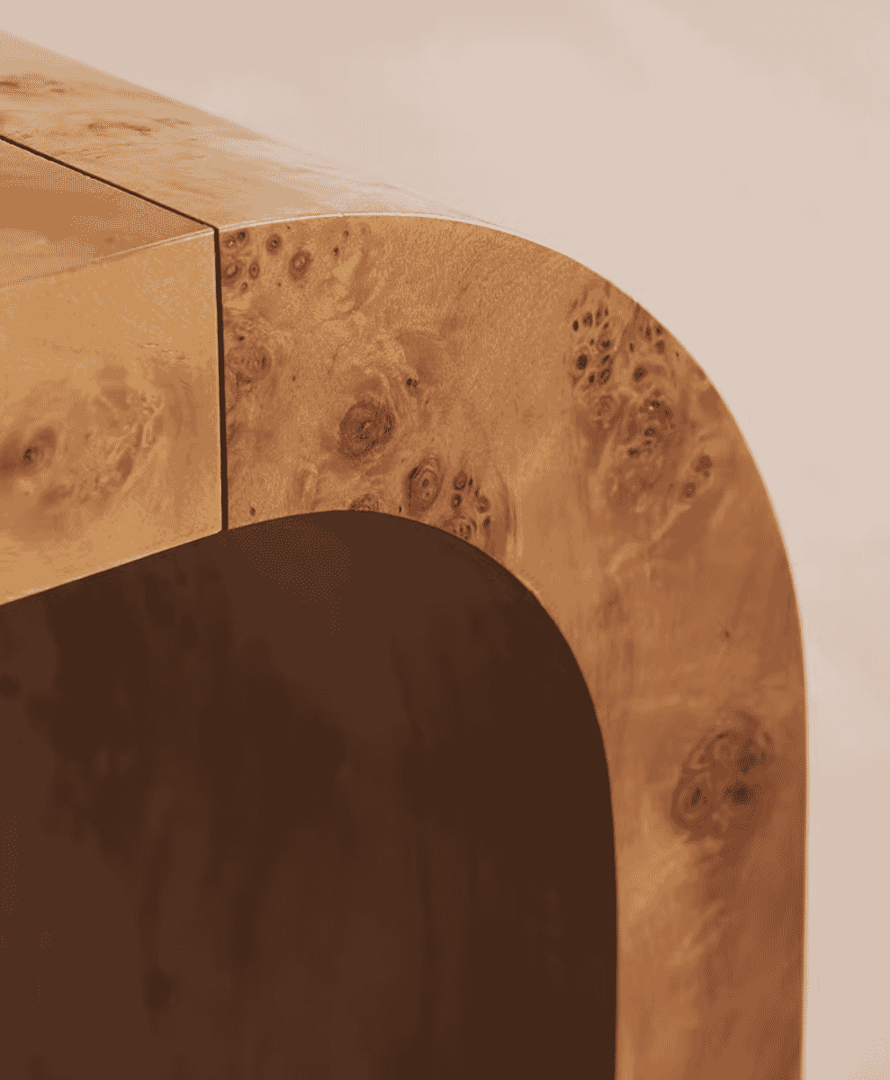 Macro shot of a curved furniture edge showcasing the intricate pattern of burl wood grain.