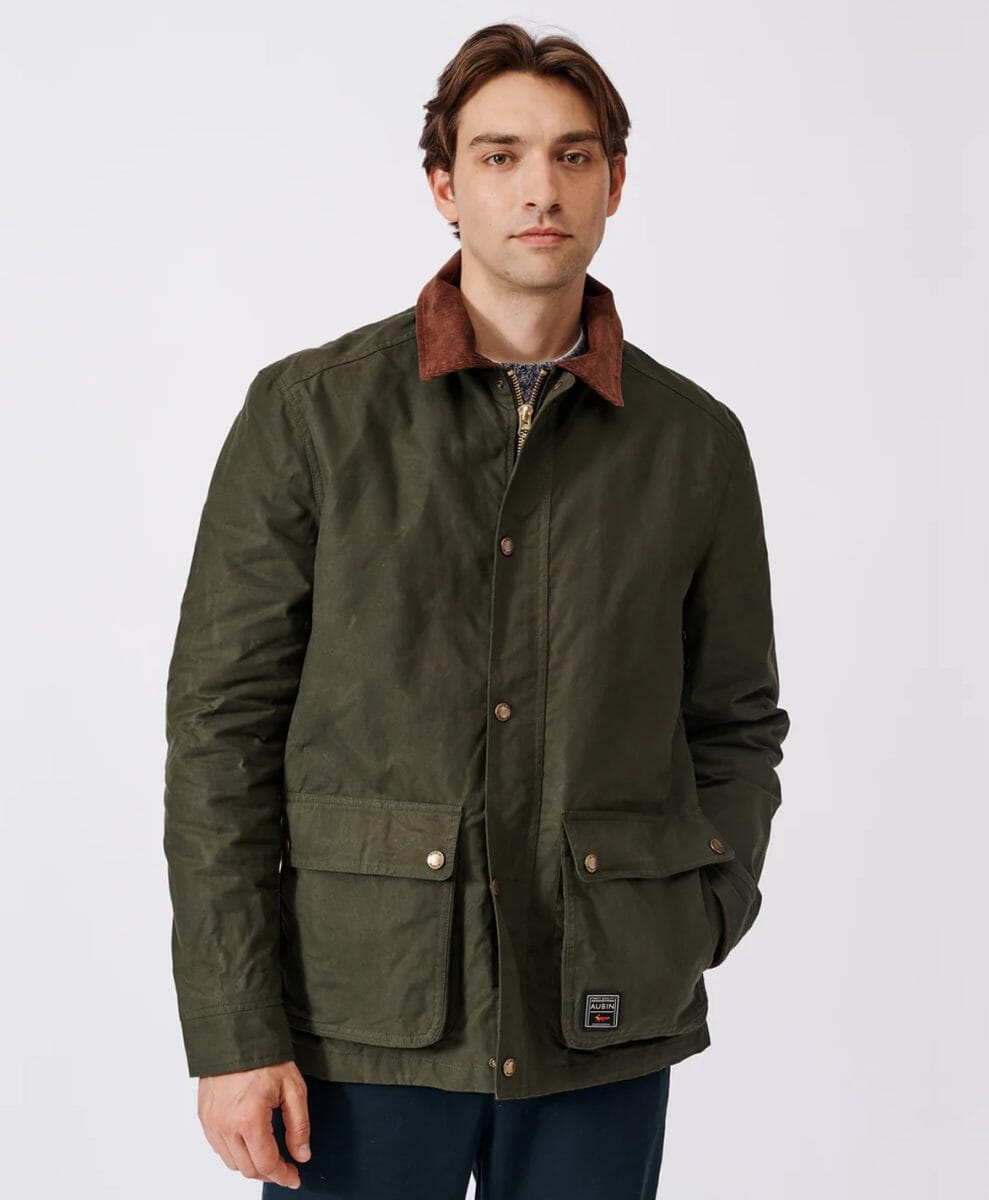 Man modeling an olive green waxed cotton jacket with a brown corduroy collar.