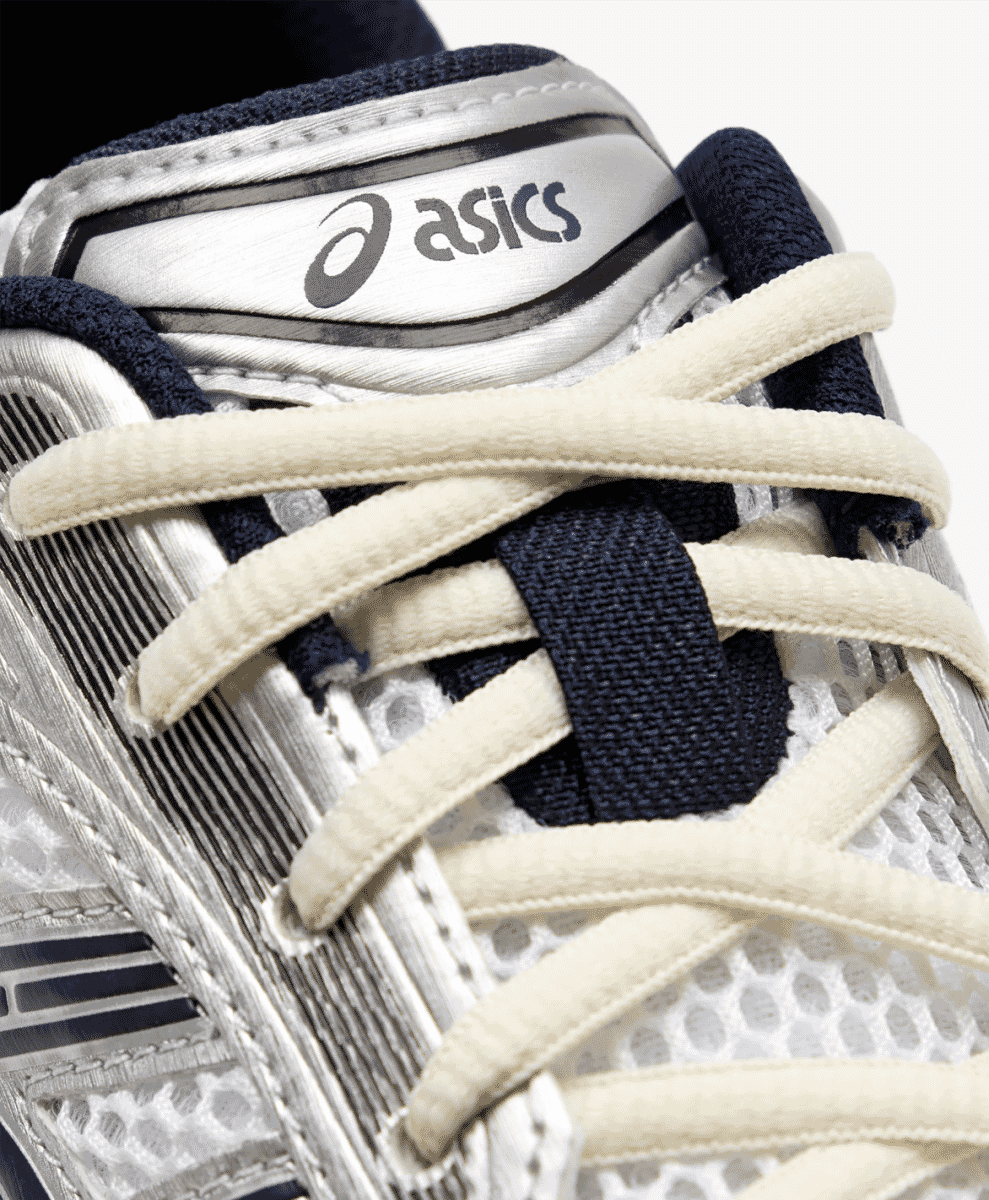 Close-up of cream laces and navy mesh details on the ASICS sneaker.