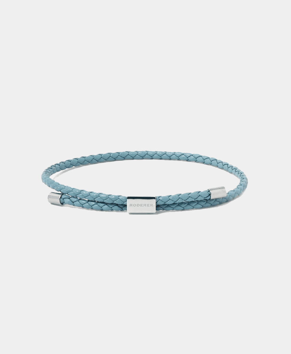 A light blue braided leather bracelet with a silver-toned clasp.