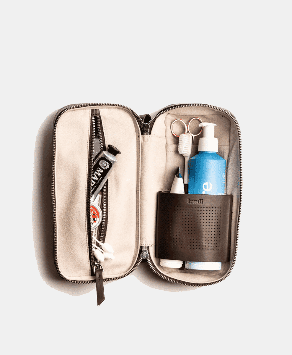 Open beige toiletry bag showing internal compartments and grooming essentials