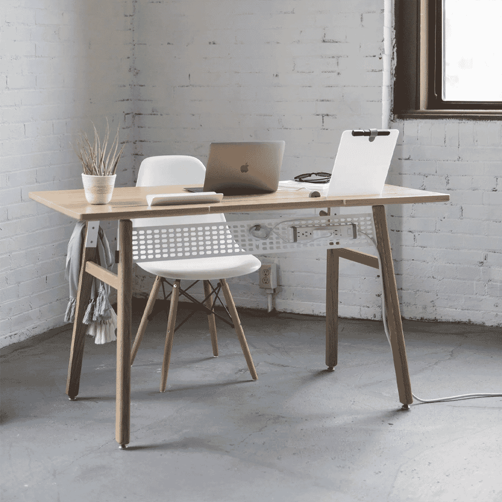 Minimalist workspace with a light wood desk and white chair against a white brick wall.