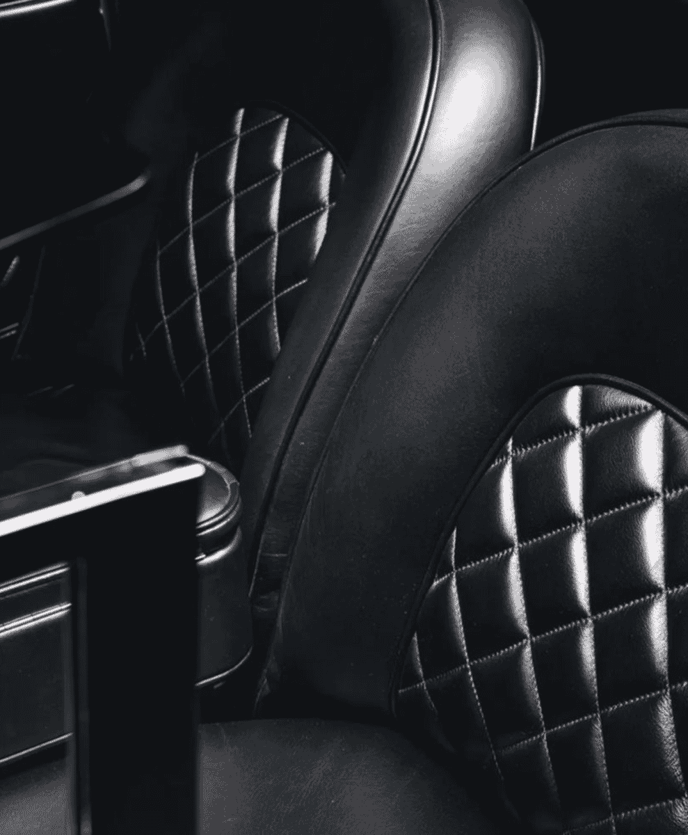 Close-up of black leather car seats with diamond-quilted stitching.