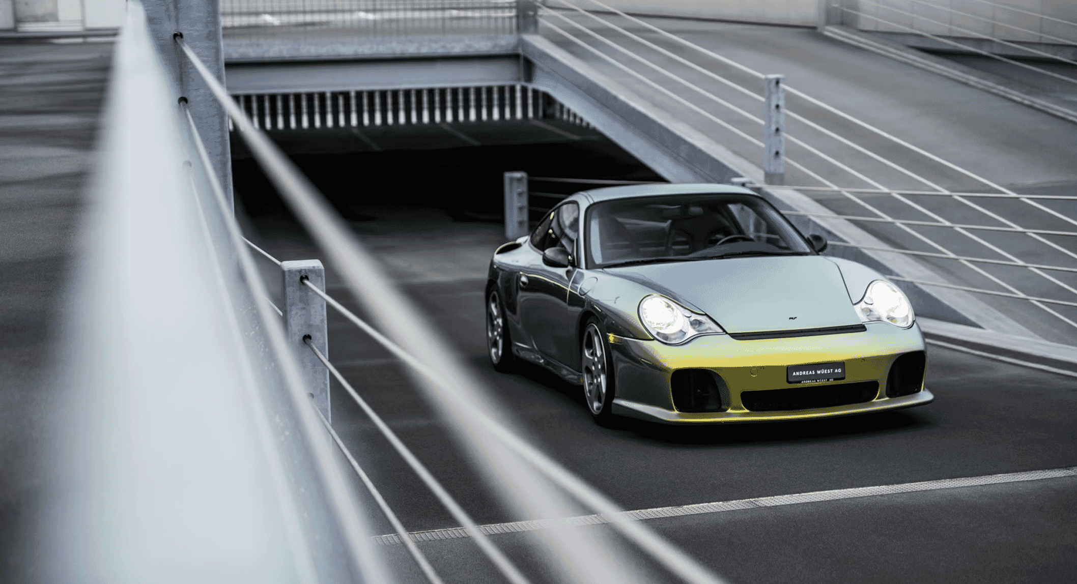 Sleek silver and yellow sports car in a modern concrete underpass with dramatic lighting.