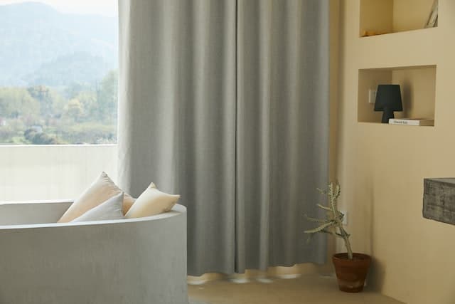 Minimalist living room with gray curtains and a large window overlooking a scenic mountain view.