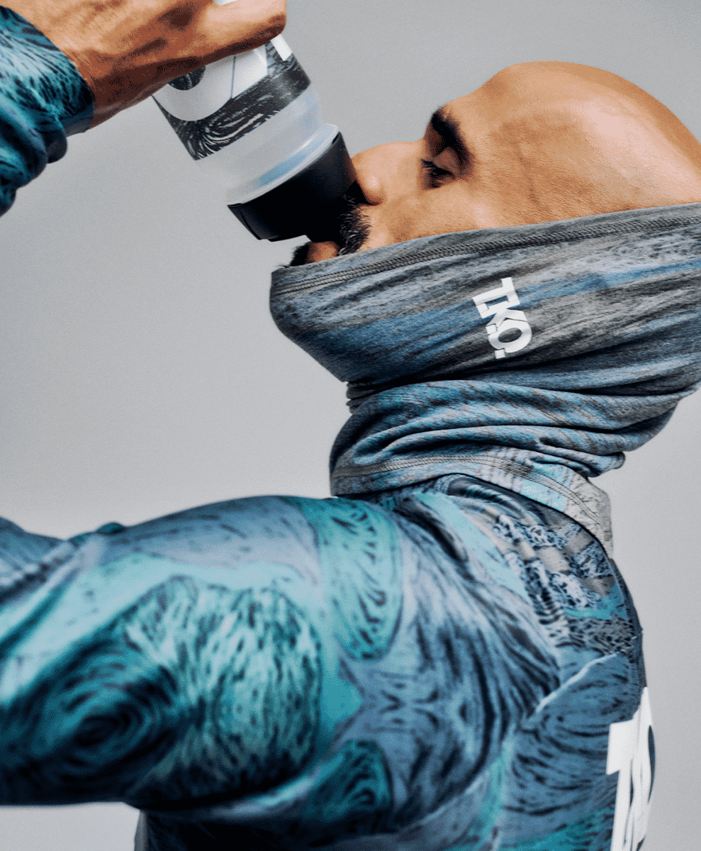 Male model in blue and gray patterned athletic top with matching neck gaiter.