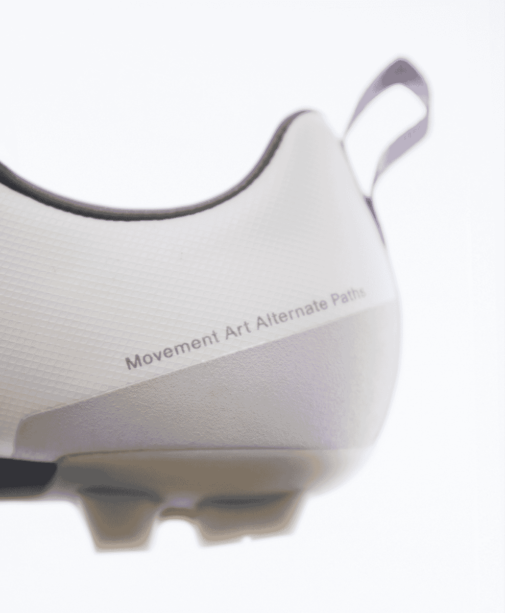 Close-up of the perforated microfiber upper and branding text on a white cycling shoe.