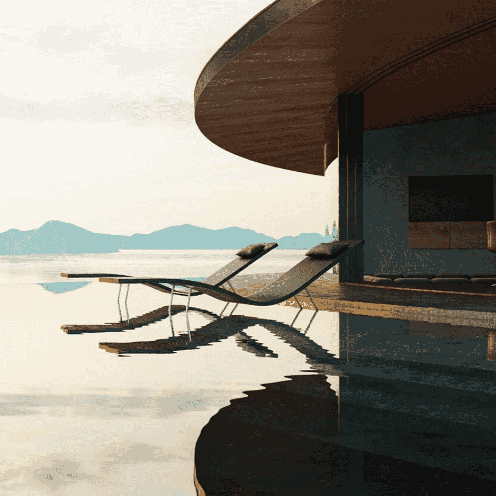Minimalist lounge chairs beside an infinity pool under a curved wooden ceiling overlooking the calm sea.
