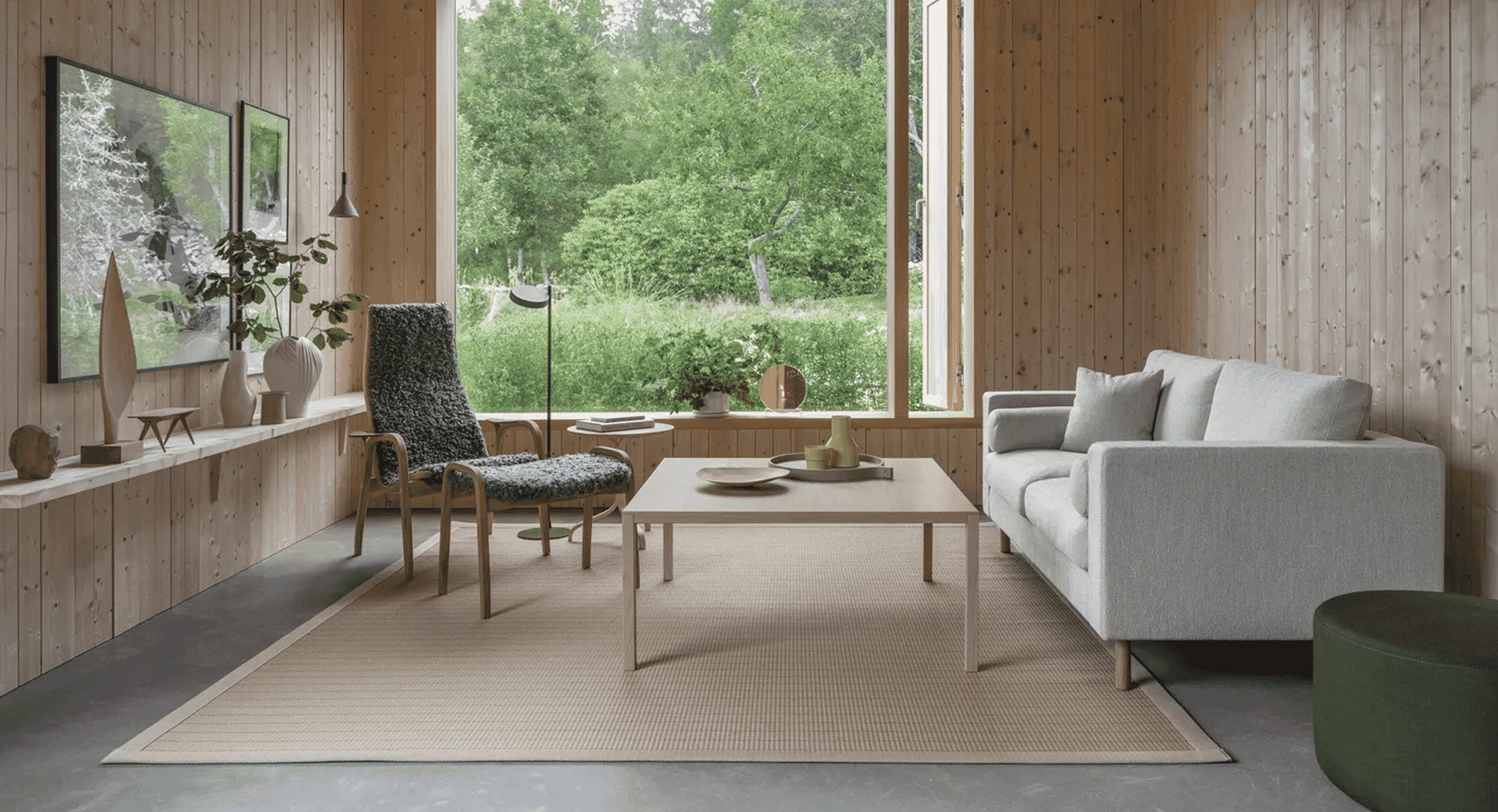 Wide-angle view of a modern Scandi living room featuring light wood walls and a central textured armchair.