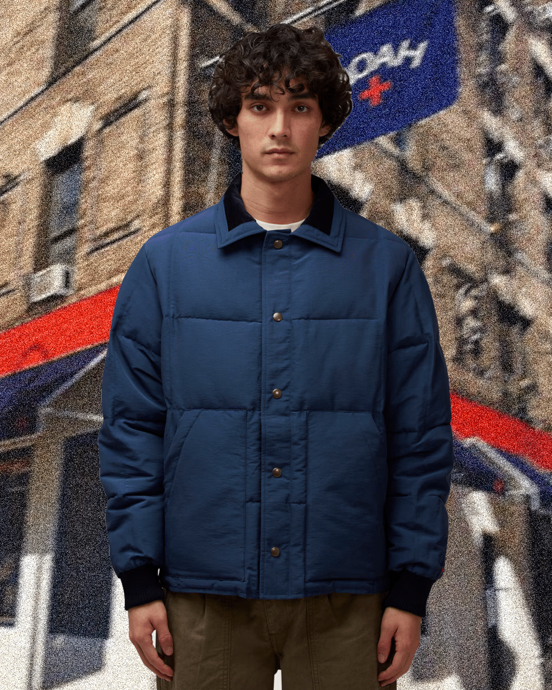 Man in a navy blue quilted puffer jacket standing in an urban environment.